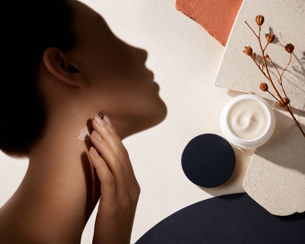 Profil de visage féminin en silhouette douce avec geste de soin sur la mâchoire