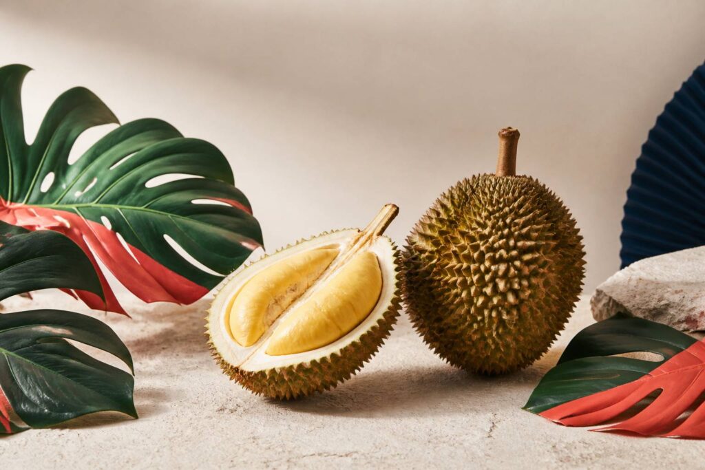 Durian entier et moitié ouverte montrant sa chair jaune crémeuse